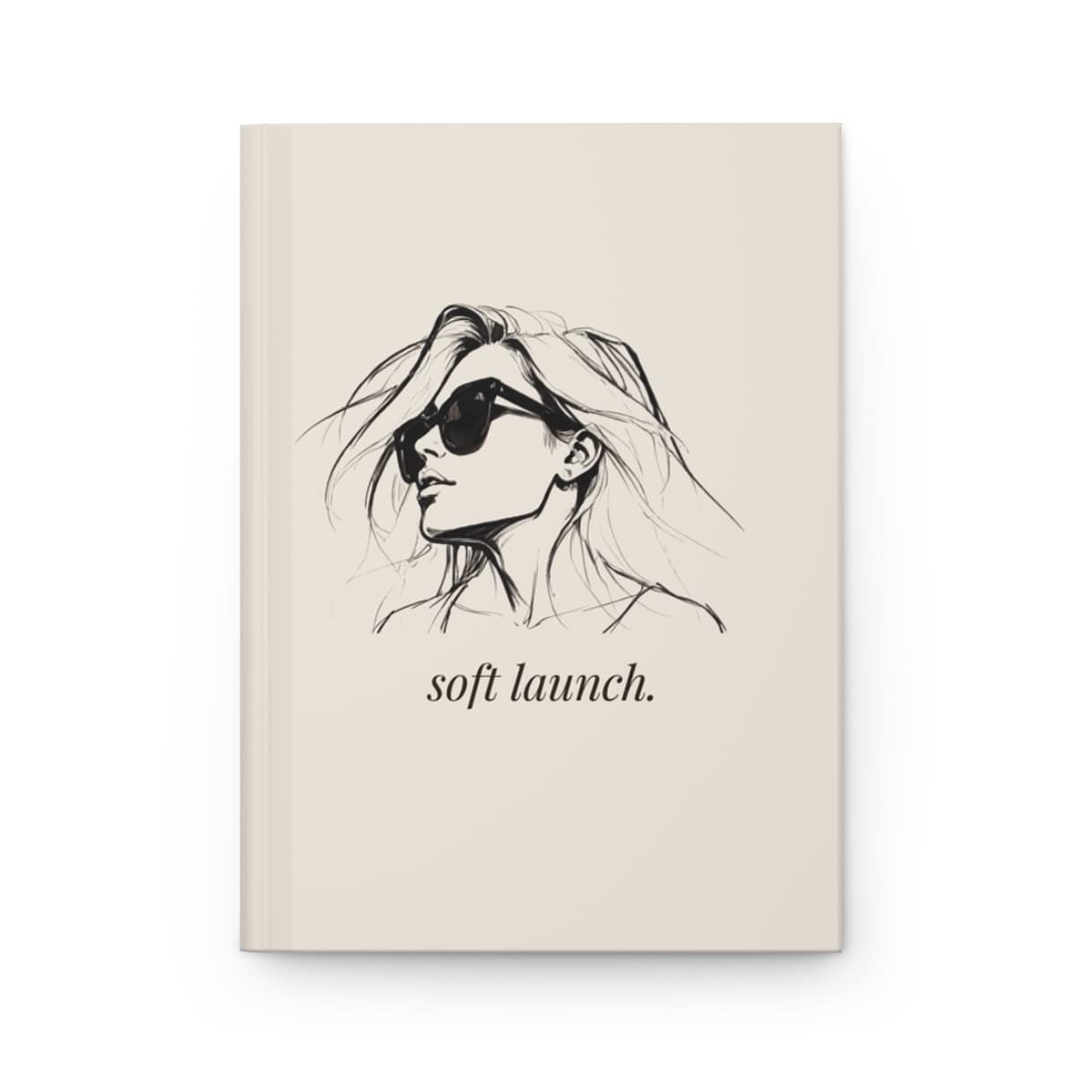 An ivory hardcover journal printed with an ink portrait of the READ ONLY woman in sunglasses above soft launch. in italic